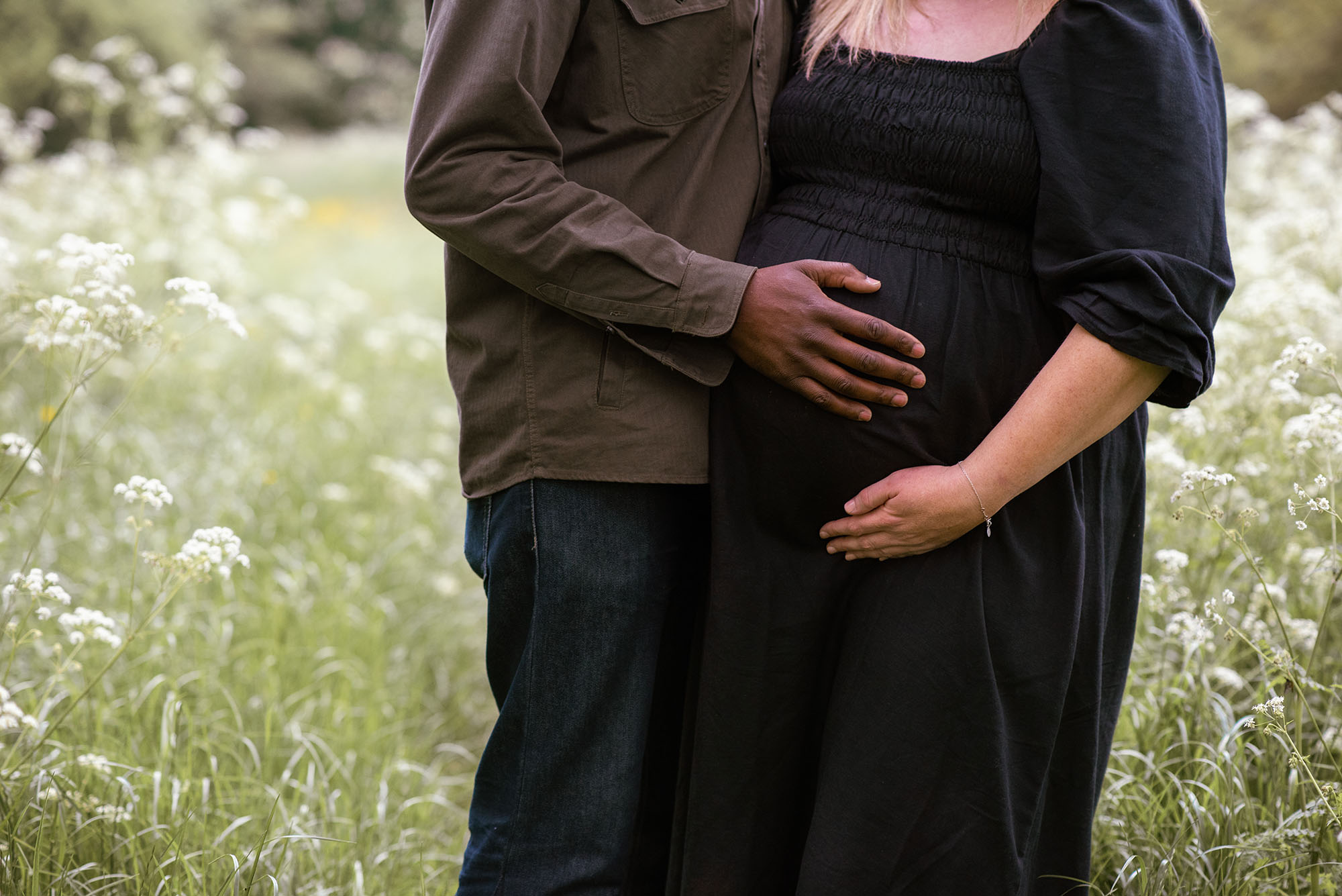 Close up image of baby bump and couple are holding it.